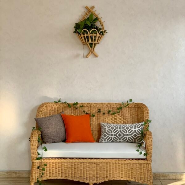 MARSA hand woven wicker loveseat with cream bench cushion against a beige wall