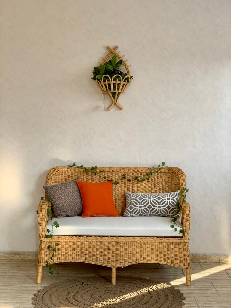 MARSA hand woven wicker loveseat with cream bench cushion against a beige wall
