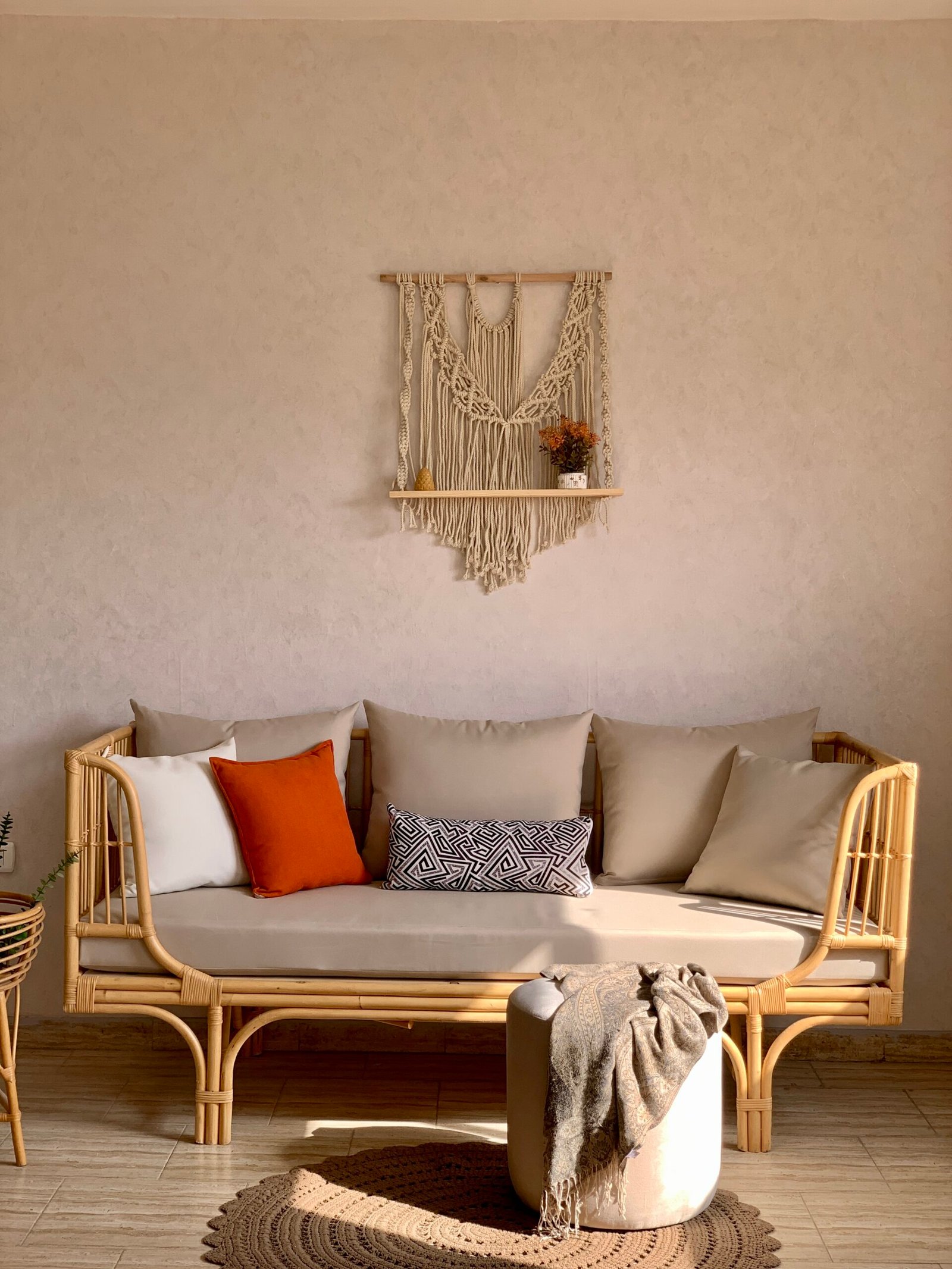 SEDRA rattan daybed sofa with beige mattress cushion under a macrame wall hanging SEDRA rattan daybed sofa with beige mattress cushion under a macrame wall hanging